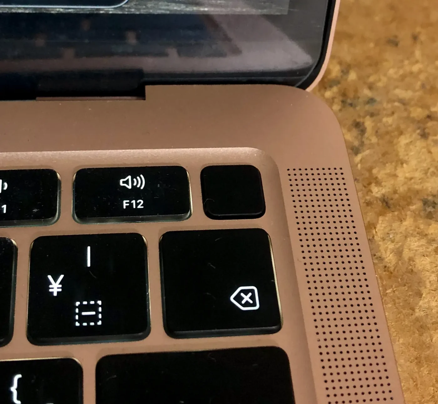 Butonul Touch ID și colțul tastaturii unui MacBook Air M1 Gold. Exemplarul fotografiat are tastatură japoneză